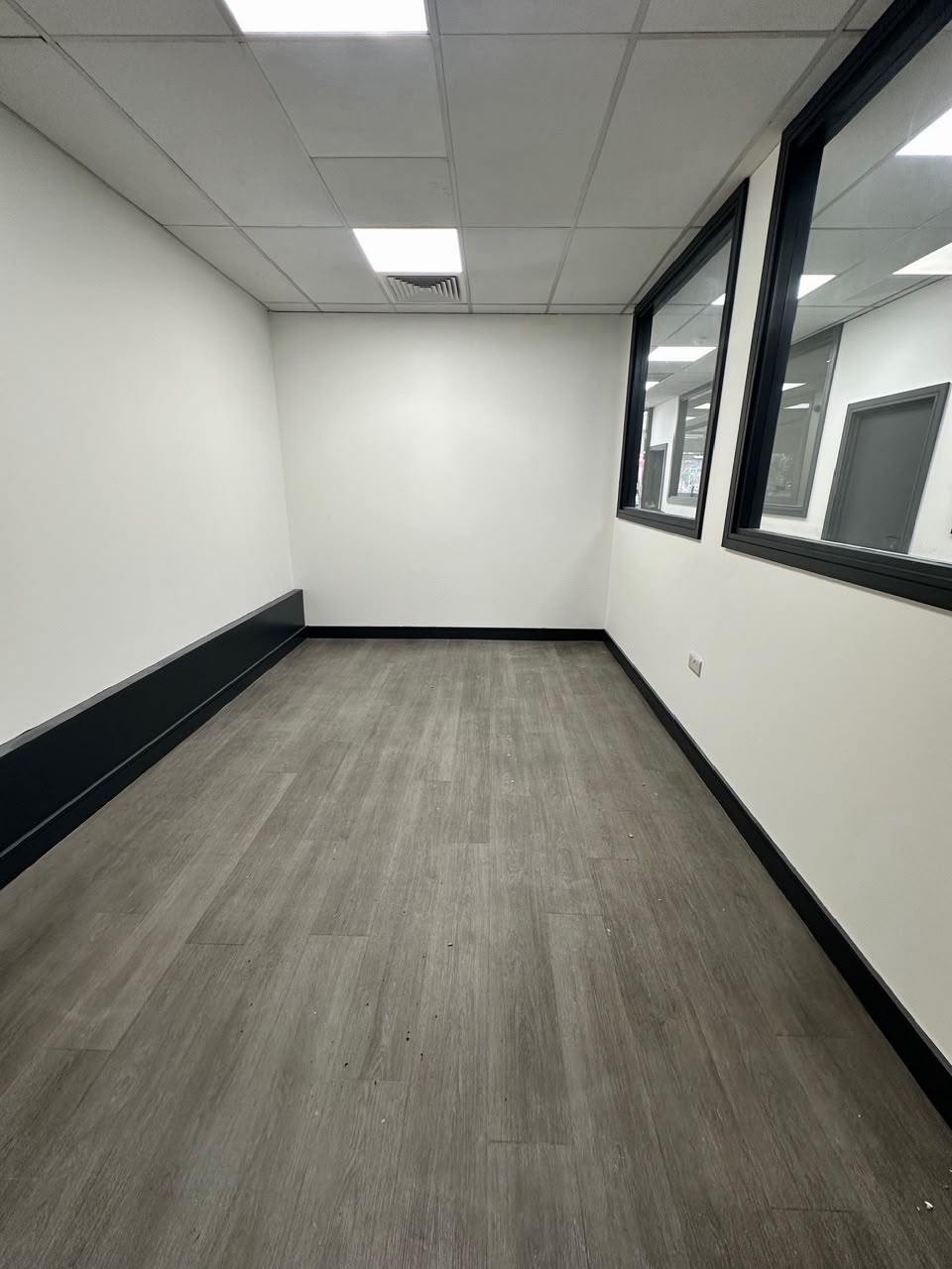 Empty unit interior with dark wood floor and panel lighting
